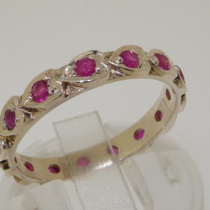 May include: A silver band ring with a row of pink ruby stones set in a delicate design.