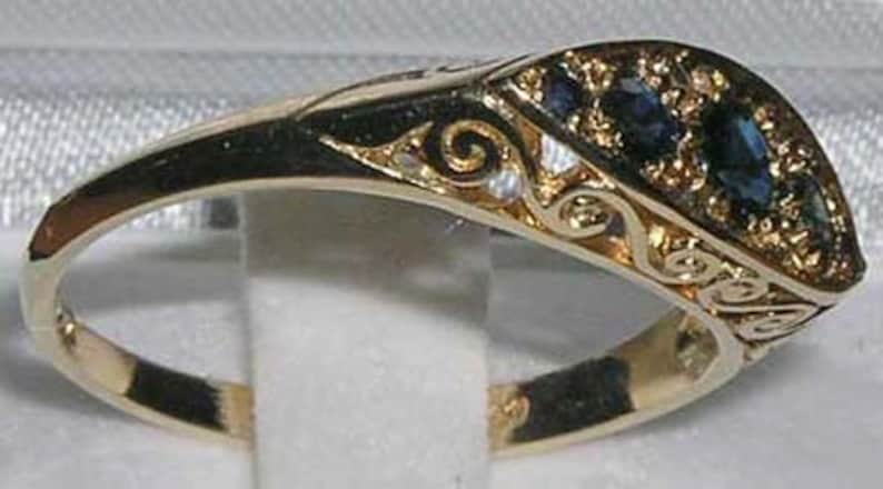 May include: A gold ring with a blue sapphire stone set in a decorative filigree design.