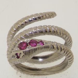 May include: A silver snake ring with three pink gemstones. The snake is coiled and has a textured surface.