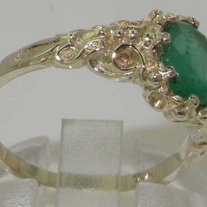 May include: A silver ring with an ornate design and a large, oval-shaped emerald gemstone.