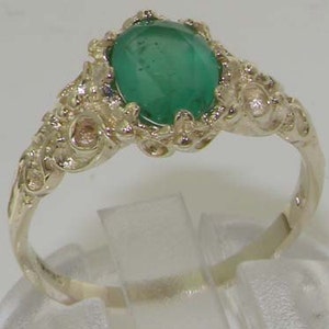 May include: A gold ring with an oval emerald gemstone set in a delicate filigree design.