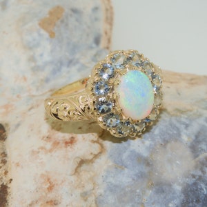 May include: A gold ring with a large white opal surrounded by a halo of smaller blue gemstones.
