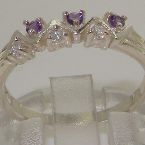 以下が含まれることがあります： ジグザグ模様にセットされた3つの紫色の宝石と3つの透明な宝石が付いたシルバーバンドリングです。