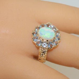 May include: A gold ring with a large oval opal surrounded by a halo of smaller blue gemstones.