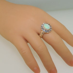 May include: A gold ring with a large oval opal surrounded by a halo of smaller blue gemstones.