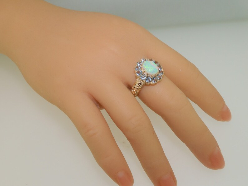 May include: A gold ring with a large oval opal surrounded by a halo of smaller blue gemstones.