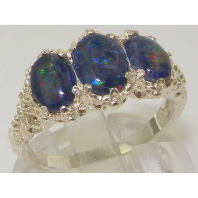 May include: A silver ring with three oval-shaped black opals set in a delicate, ornate design.