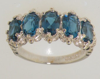 Puede incluir: Un anillo de plata con cinco topacios azules ovalados engastados en un delicado diseño floral.