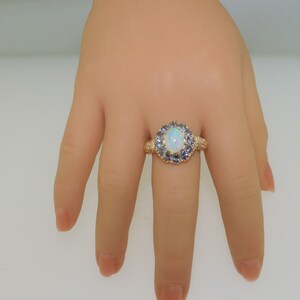 May include: A gold ring with a large white opal surrounded by a halo of smaller blue gemstones.
