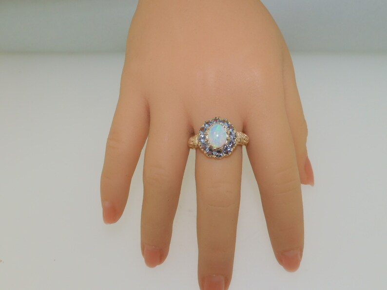 May include: A gold ring with a large white opal surrounded by a halo of smaller blue gemstones.