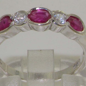 May include: A silver band ring with three pink ruby stones and two clear diamond stones.