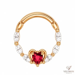 May include: A circular hoop ring in a warm gold tone featuring a series of marquise-cut clear stones along the band. At the bottom center, a heart-shaped red stone is set within a gold frame. The brand name VELTRION JEWELS appears in the corner.