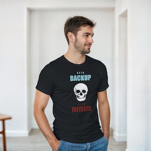 May include: Black t-shirt with a white skull graphic and the text "KEIN BACKUP KEIN MITLEID" in blue and red. The shirt is made of a soft material and is being worn by a person.