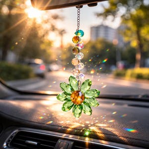 Peut inclure: Un ornement de voiture suspendu composé d'une fleur en cristal vert à facettes avec un centre ambré, attaché à une chaîne en métal argenté ornée d'une série verticale de perles en cristal transparentes, irisées et multicolores.