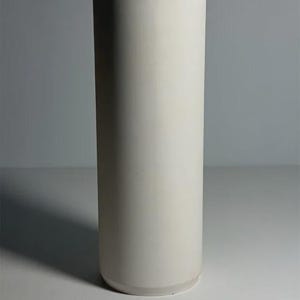 May include: A tall, cylindrical vase with a smooth, matte off-white finish. The vessel features a simple, straight-sided design with a flat top opening and a solid, uniform structure, presenting a clean and neutral appearance throughout the object.