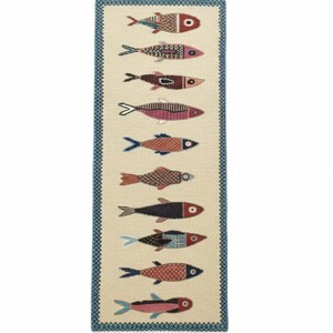 May include: A rectangular woven runner rug featuring a cream-colored background with a repeating pattern of ten stylized fish in various colors including red, blue, brown, and pink. The rug is bordered by a blue geometric trim and fringed ends.