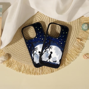 May include: Two black phone cases featuring a graphic illustration of a silhouette of a person and a cat walking under a large white moon against a dark blue starry sky with swirling patterns and dark tree branches on the sides.
