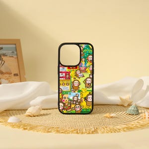 May include: A black smartphone case featuring a vibrant collage of cartoon monkeys, yellow bananas, and Japanese text on a multi-coloured background. The design includes various small illustrations of monkeys in different poses, speech bubbles, and bright graphic elements.