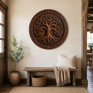 May include: A circular wooden wall art piece featuring a detailed relief carving of a tree with intricate roots and foliage. The design is enclosed within a decorative border with a woven pattern, showcasing a rich brown wood grain finish.