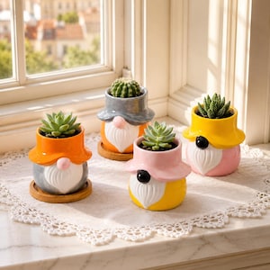 May include: Four ceramic gnome-shaped planters, each holding a small succulent plant. The planters feature colorful hats in orange, gray, yellow, and pink, with white beards and round noses. Each gnome sits on a small, round wooden base.