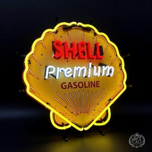 Puede incluir: Un letrero de neón con forma de concha que presenta un fondo amarillo con un borde rojo. El texto SHELL aparece en neón rojo, la palabra Premium en neón blanco y la palabra GASOLINE está impresa en letras rojo oscuro bajo los elementos.