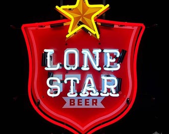 May include: A neon sign with a red shield shape, featuring the words "LONE STAR BEER" in white neon. A yellow star sits atop the shield. The sign is against a black background.
