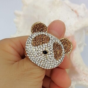 May include: A gold-toned ring featuring a bear-shaped face encrusted with clear and brown rhinestones. The bear design includes two brown-filled ears, brown patches around the eyes, a white-rhinestone face, and a single small black stone for the nose.