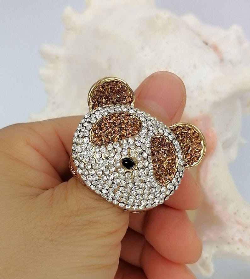 May include: A gold-toned ring featuring a bear-shaped face encrusted with clear and brown rhinestones. The bear design includes two brown-filled ears, brown patches around the eyes, a white-rhinestone face, and a single small black stone for the nose.