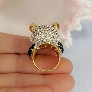 Peut inclure: Une bague dor&eacute;e en forme de t&ecirc;te de panda, dot&eacute;e d'un anneau et d'oreilles en m&eacute;tal dor&eacute; poli. Le sommet de la t&ecirc;te est recouvert de strass blancs transparents, tandis que les oreilles et le contour des yeux sont orn&eacute;s de petits strass noirs.