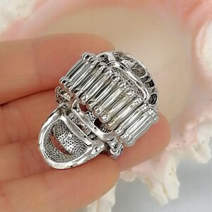 May include: A silver-toned ring featuring a wide, flexible band constructed from multiple vertical metal bars. The ring has a textured, open-work design with a metallic finish, showcasing a structured, cage-like appearance across the entire surface.