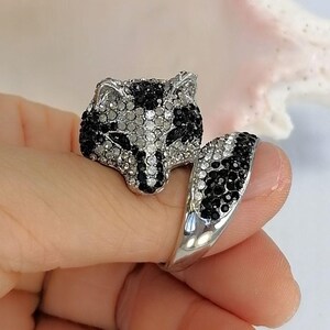 Pu&ograve; includere: Un anello color argento a forma di testa di volpe con un design a coda avvolgente. La superficie &egrave; incastonata con numerosi piccoli cristalli scintillanti trasparenti e neri che formano i tratti del viso e il motivo a strisce della coda.