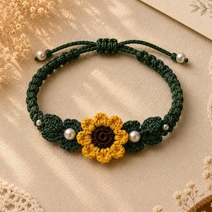 May include: Handmade green macrame bracelet featuring a yellow and brown crochet sunflower and green leaves. The bracelet is adorned with white pearl beads. The adjustable bracelet is a charming accessory.