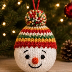 May include: A round, white crocheted snowman ornament featuring a knitted hat with red, yellow, and green horizontal stripes, topped with a multicolored pom-pom and a red hanging loop. The face has black embroidered eyes, eyebrows, and a smile.