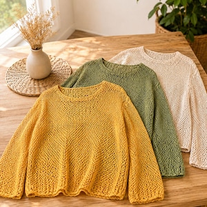 May include: Three long-sleeve sweaters featuring an open-knit mesh pattern. The sweaters are presented in solid mustard yellow, olive green, and cream colors, each designed with a rounded neckline and a relaxed fit with ribbed cuffs and hem.