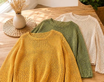May include: Three long-sleeve sweaters featuring an open-knit mesh pattern. The sweaters are presented in solid mustard yellow, olive green, and cream colors, each designed with a rounded neckline and a relaxed fit with ribbed cuffs and hem.