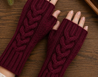 May include: A pair of deep burgundy fingerless gloves featuring a prominent vertical cable knit pattern running down the center. The gloves have a ribbed cuff at the wrist and a ribbed opening for the fingers, crafted from a thick, textured knit fabric.