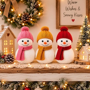 Puede incluir: Tres figuras de muñecos de nieve de peluche con cuerpos de punto blanco, cada una con un gorro de punto a juego con un pompón y una bufanda. Los muñecos de nieve tienen accesorios de color rosa, amarillo mostaza y rojo, narices naranjas.