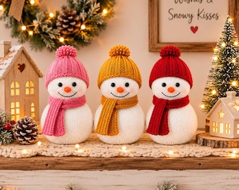 May include: Three plush snowman figurines with white knit bodies, each wearing a matching colored knit hat with a pom-pom and a scarf. The snowmen feature pink, mustard yellow, and red accessories, orange carrot noses, and black eyes.