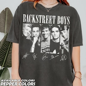 Könnte beinhalten: Ein anthrazitfarbenes Kurzarm-T-Shirt mit dem Schriftzug BACKSTREET BOYS in fetter weißer Schrift. Unter dem Text befinden sich Schwarz-Weiß-Porträts der fünf Bandmitglieder, jeweils mit einer darunter gedruckten weißen Unterschrift.