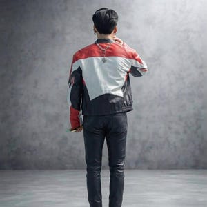 May include: A color-blocked leather jacket featuring red, white, and black panels with a silver-toned chain necklace worn around the neck, paired with black leather trousers. The jacket has a structured fit and long sleeves, shown from the back.