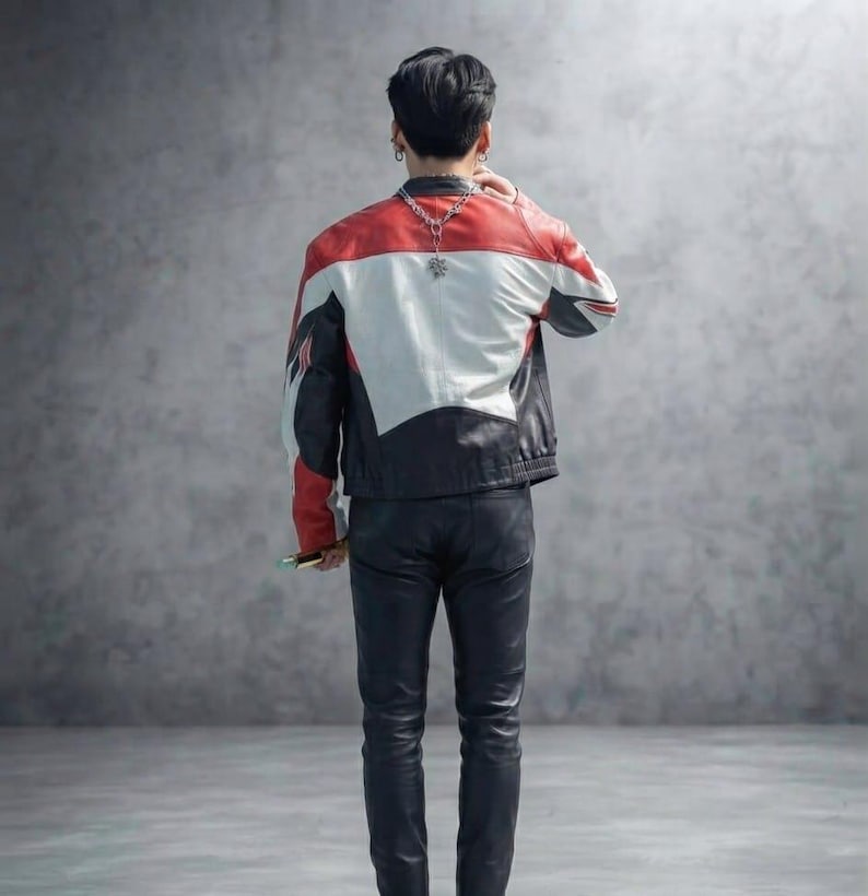 May include: A color-blocked leather jacket featuring red, white, and black panels with a silver-toned chain necklace worn around the neck, paired with black leather trousers. The jacket has a structured fit and long sleeves, shown from the back.