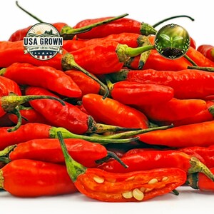 May include: A pile of vibrant red chili peppers with green stems. One pepper is cut open, revealing seeds. The image includes two circular logos: one with "USA Grown" and the other with a sprouting plant.