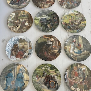 Op de afbeelding: Een verzameling van twaalf ronde decoratieve keramische borden gerangschikt in een raster, elk met gedetailleerde, kleurrijke illustraties van antropomorfe dieren in diverse historische settings, inclusief scènes met oldtimers en treinen.