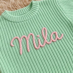 Grüner Baby-Strickpullover mit individuellem Namen, personalisierter Pullover mit rosa Schreibschrift, handgefertigter Baby-Jumper, Geschenk zur Babyparty oder zum Geburtstag