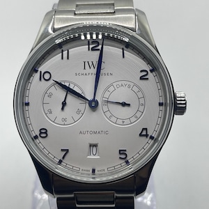 May include: A silver wristwatch with a white face, black numerals, and hands. The watch displays the text "IWC SCHAFFHAUSEN AUTOMATIC SWISS MADE". It has two sub-dials and a silver-toned metal strap. The watch is approximately 4 cm in diameter.