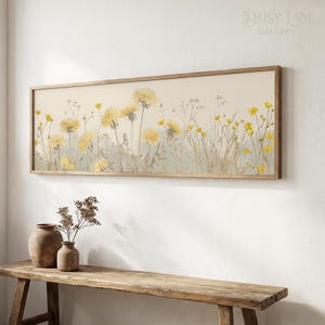 Könnte beinhalten: Ein rechteckiger Wandkunstdruck in einem Holzrahmen mit einer horizontalen Illustration von gelben Löwenzahnblüten und Wildblumen vor einem cremefarbenen Hintergrund. Das Kunstwerk zeigt verschiedene Stängel und Blüten in Gelb- und gedämpften Grüntönen.