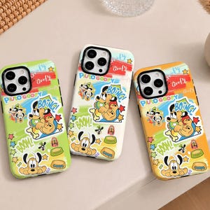 May include: Three smartphone cases featuring a colorful collage of Disney characters Pluto and Goofy. The designs include the text Pluto, Goofy, Boing, and Boom, alongside star shapes and bone icons, set against lime green, white, and orange backgrounds.