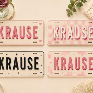 May include: Four rectangular license plates featuring the name KRAUSE in various styles. One is cream with pink hearts, one has a pink checkerboard pattern, one is cream with black stars, and one features a pink cloud pattern with small stars.