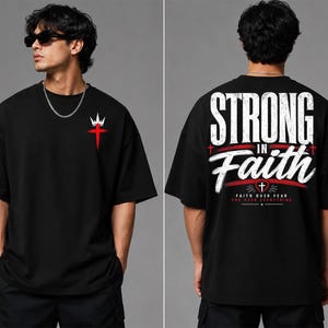 May include: A black short-sleeve t-shirt featuring a small red cross with a white crown on the front chest. The back displays the large white text "STRONG IN FAITH" with a red heart, a small cross, and the text "FAITH OVER FEAR GOD OVER EVERYTHING."