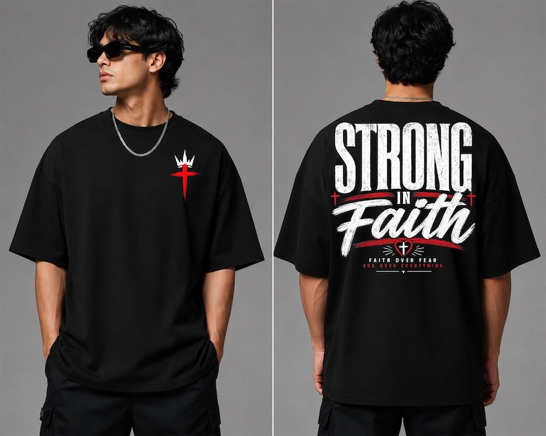 May include: A black short-sleeve t-shirt featuring a small red cross with a white crown on the front chest. The back displays the large white text "STRONG IN FAITH" with a red heart, a small cross, and the text "FAITH OVER FEAR GOD OVER EVERYTHING."